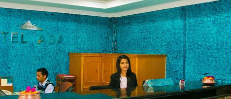 A reception desk with a blue textured wall, a wooden cabinet, and a sign that reads "RECEPTION".