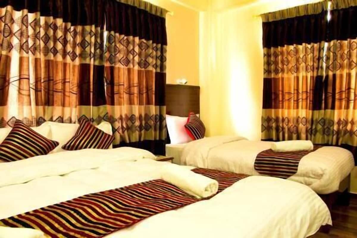 Ein Hotelzimmer mit zwei Betten, gemusterten Vorhängen und einem Kopfteil.