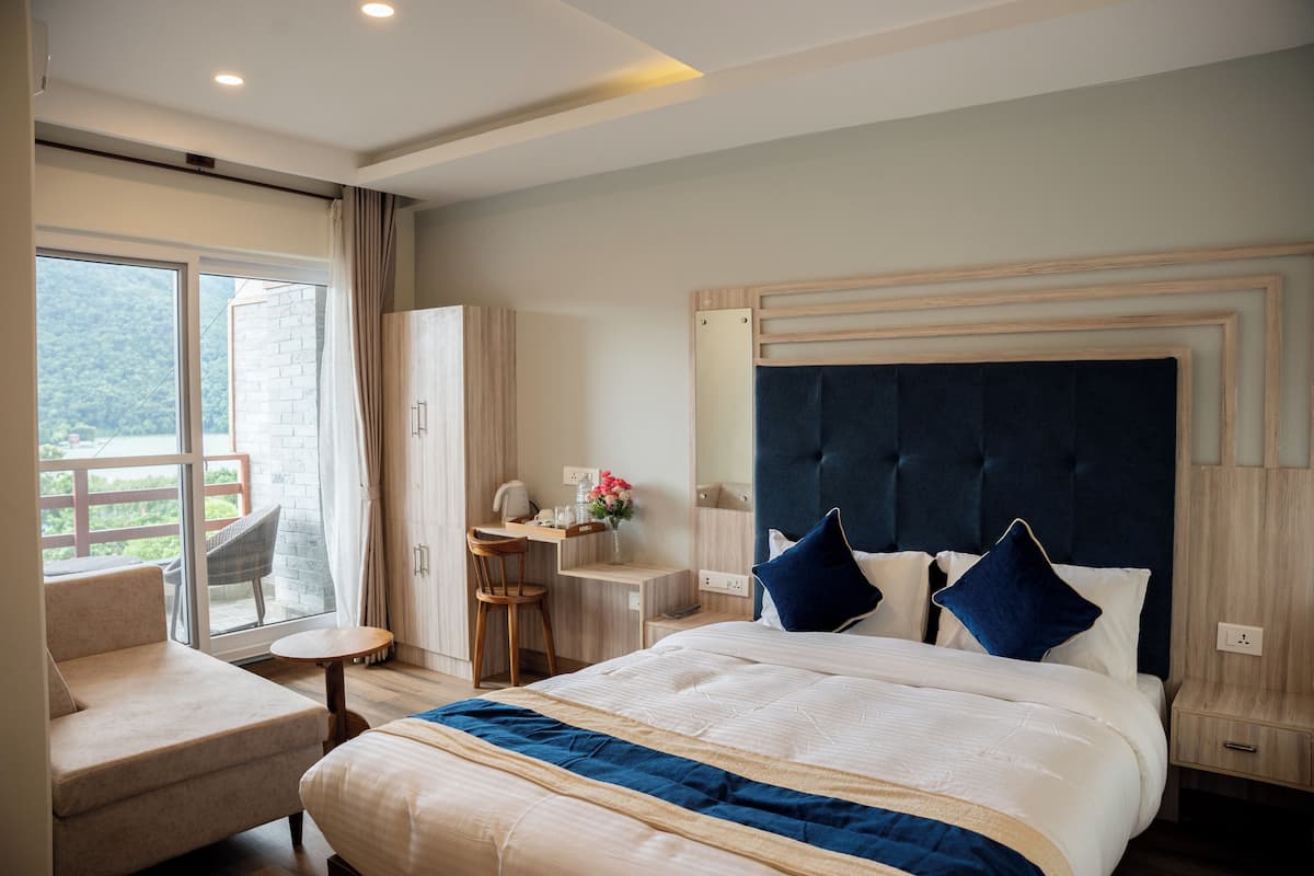 Ein Hotelzimmer mit einem großen Bett, einem Schreibtisch, einem Sessel und einem Balkon mit Bergblick.