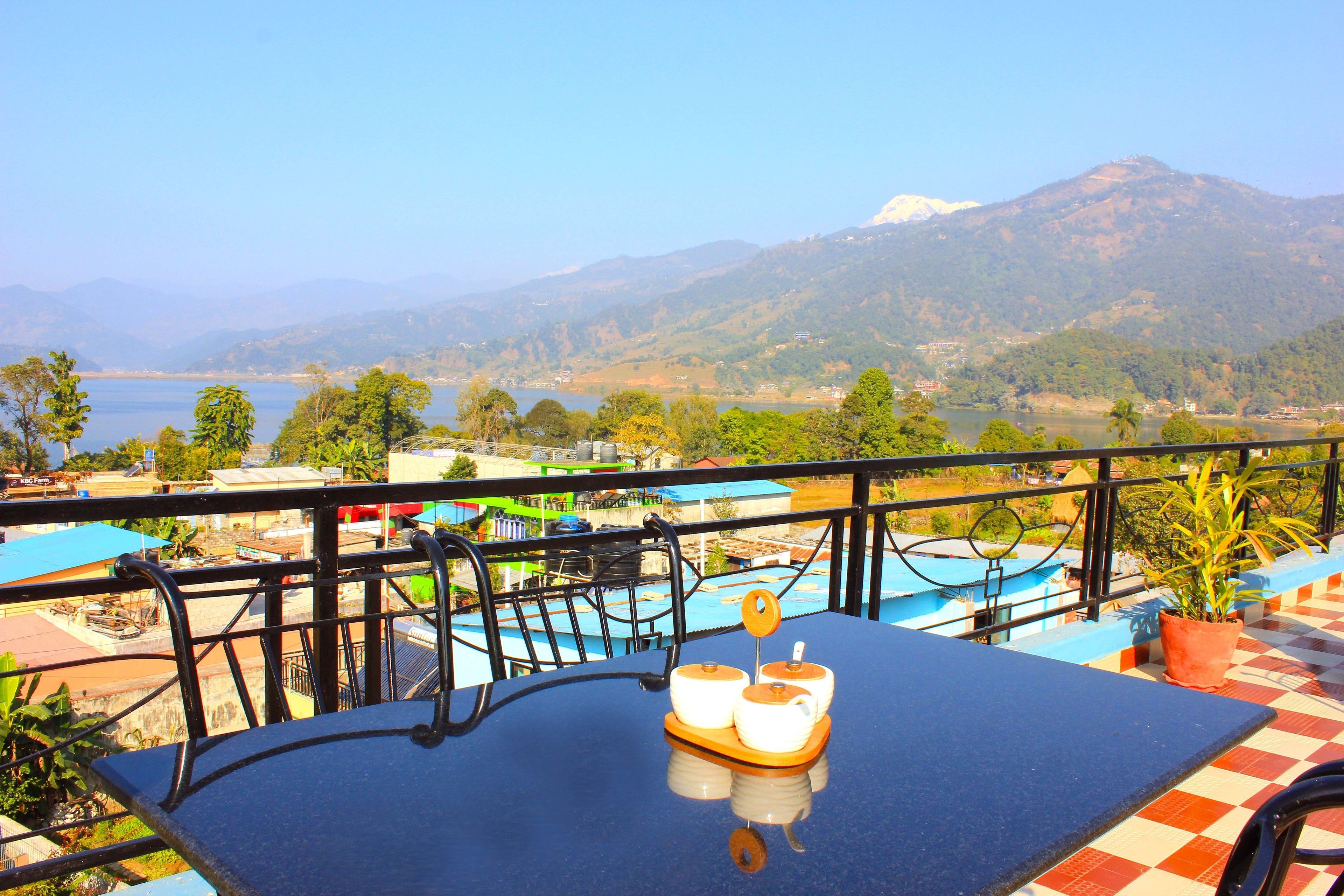 Una terraza con una mesa, sillas y vistas a una montaña y un lago.