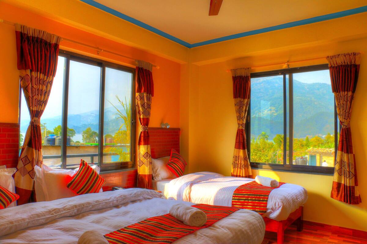 Ein Hotelzimmer mit zwei Betten, großen Fenstern und Bergblick.