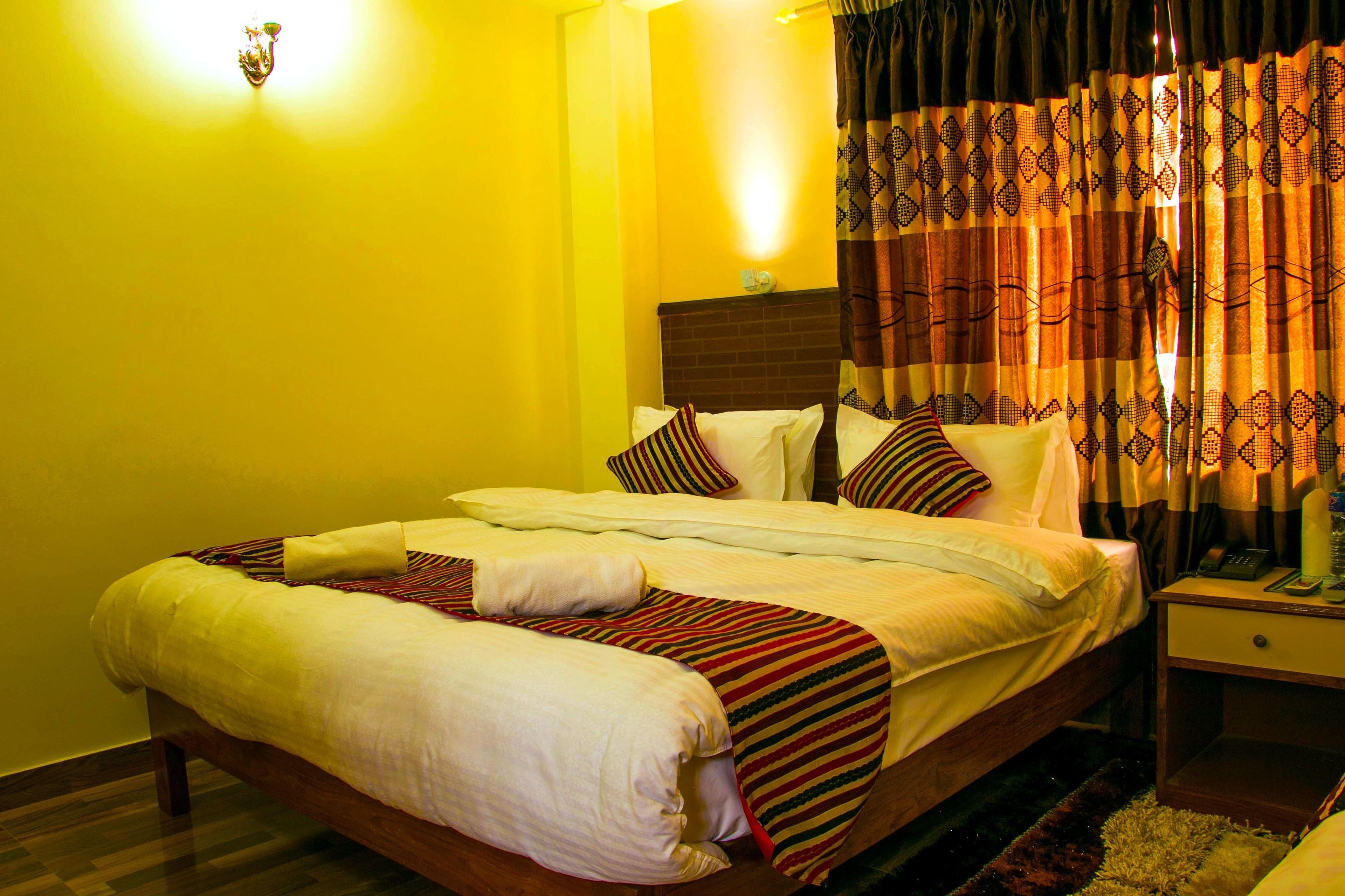 A bed with a striped bedspread, pillows, and a bedside table with a lamp.