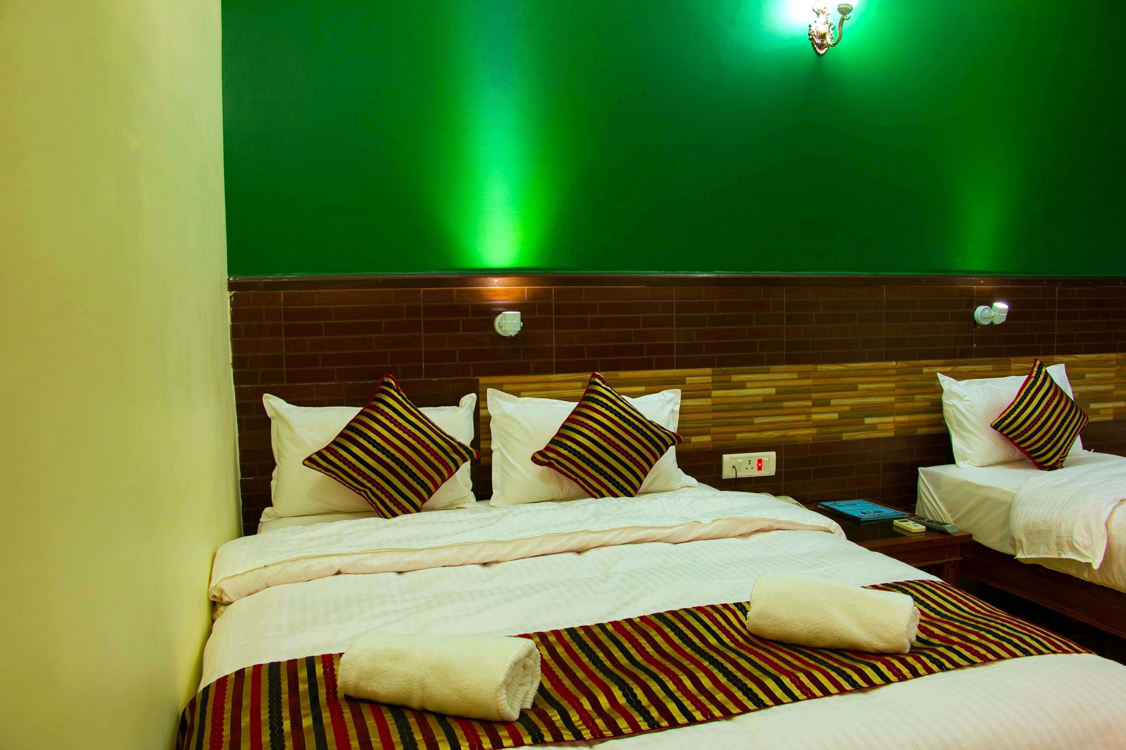 Una habitación de hotel con dos camas, una pared de ladrillo y una pared verde.