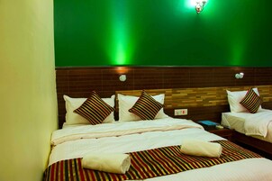 Una habitación de hotel con dos camas, una pared de ladrillo y una pared verde.