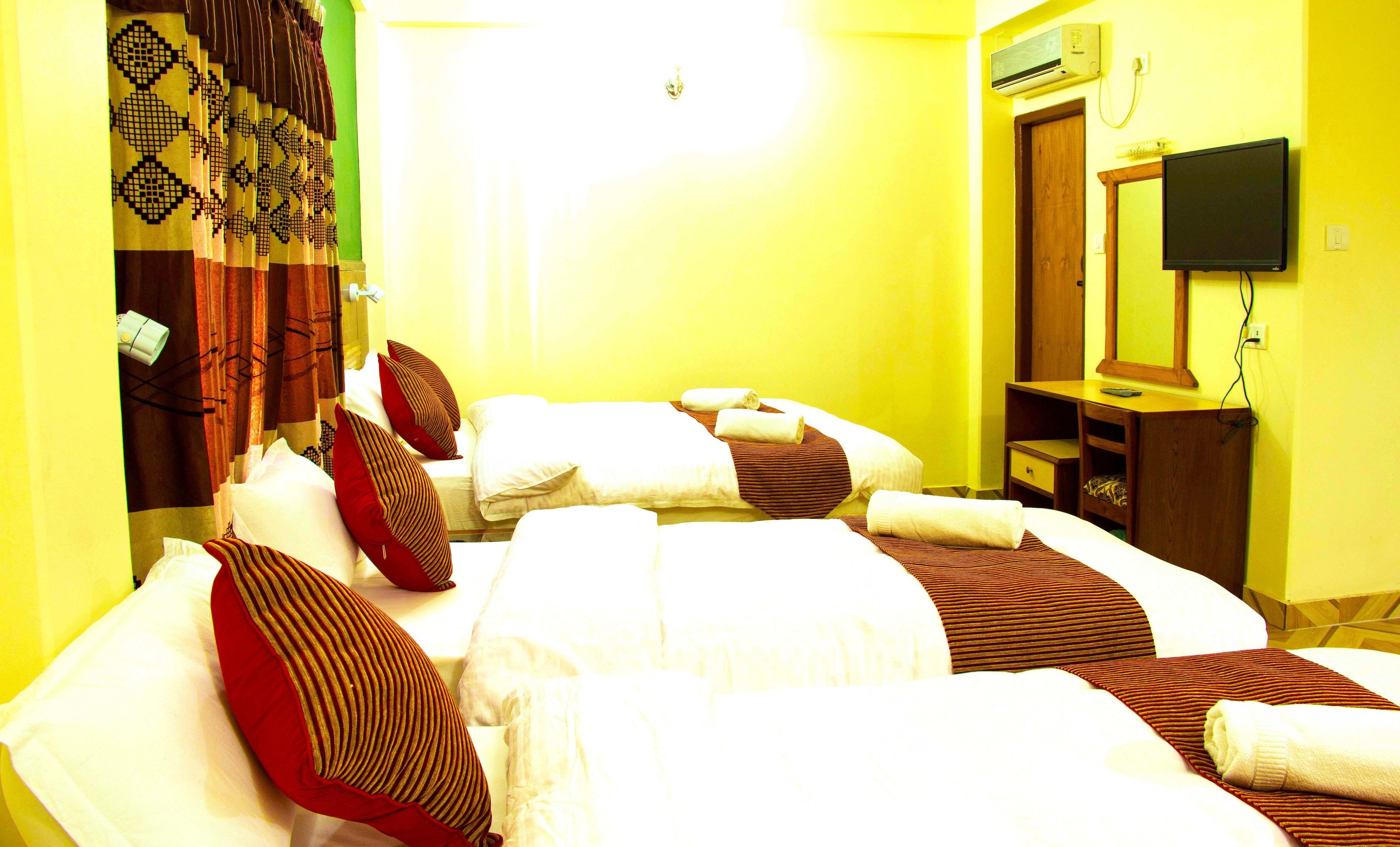 A hotel room with two beds, a TV, a desk, and a mirror.