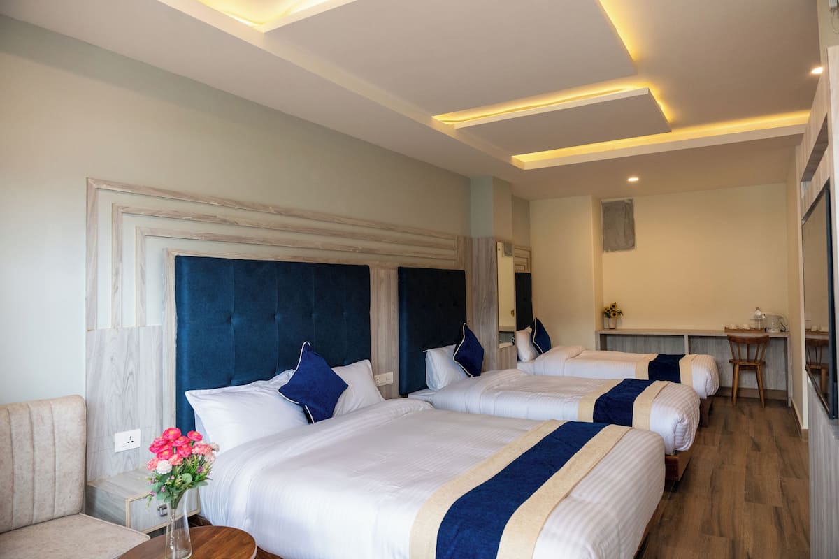 Ein Hotelzimmer mit drei Betten, einem Schreibtisch und einem Stuhl.