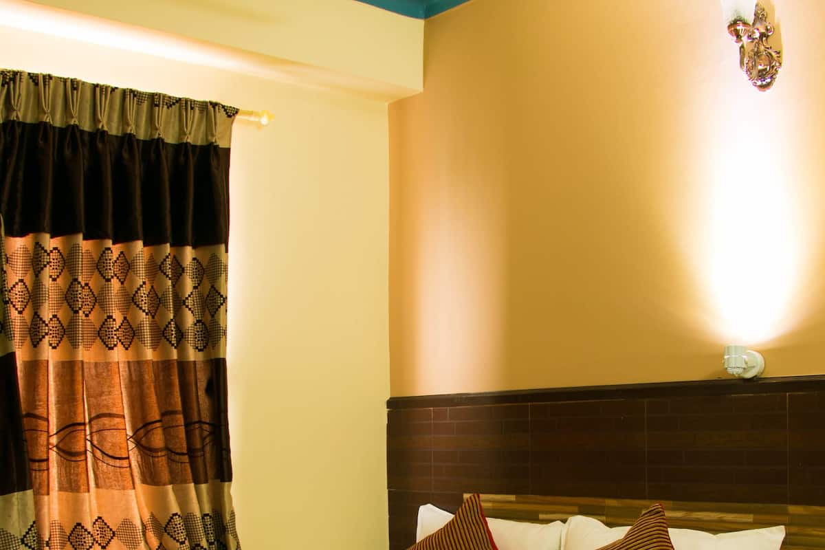 Ein Hotelzimmer mit einem Bett, einem Nachttisch, einer Lampe und einem Vorhang.