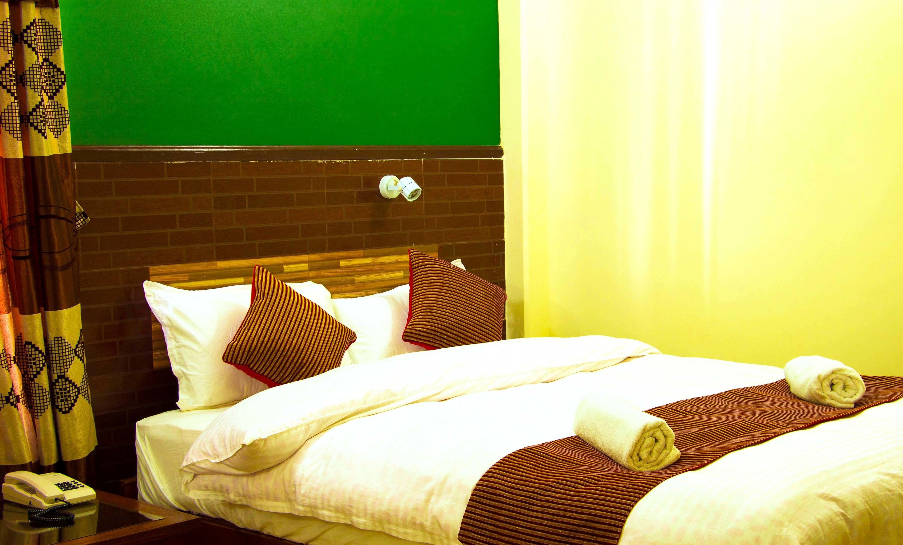 Una habitación de hotel con una cama, un teléfono y una pared de ladrillo.