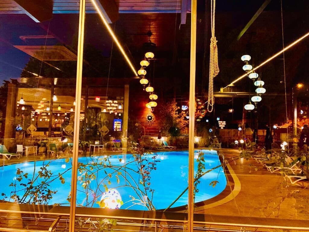 Una piscina rodeada de sillas y mesas de descanso, con una zona de bar al fondo.