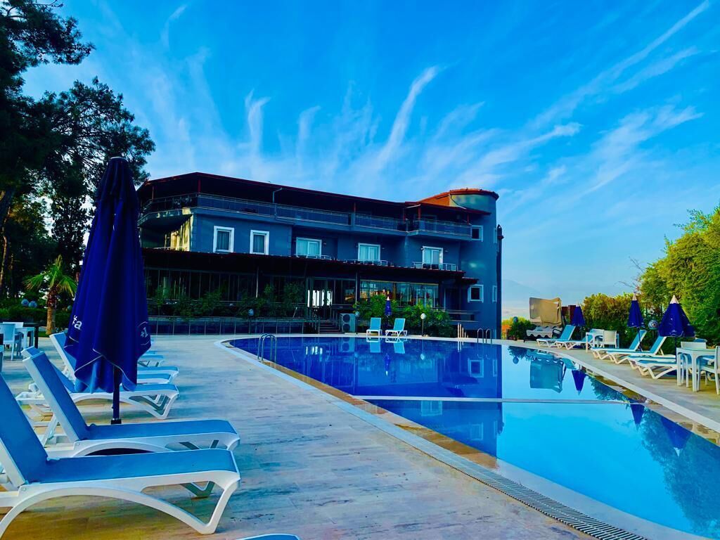 A modern hotel with a pool, lounge chairs, and umbrellas.