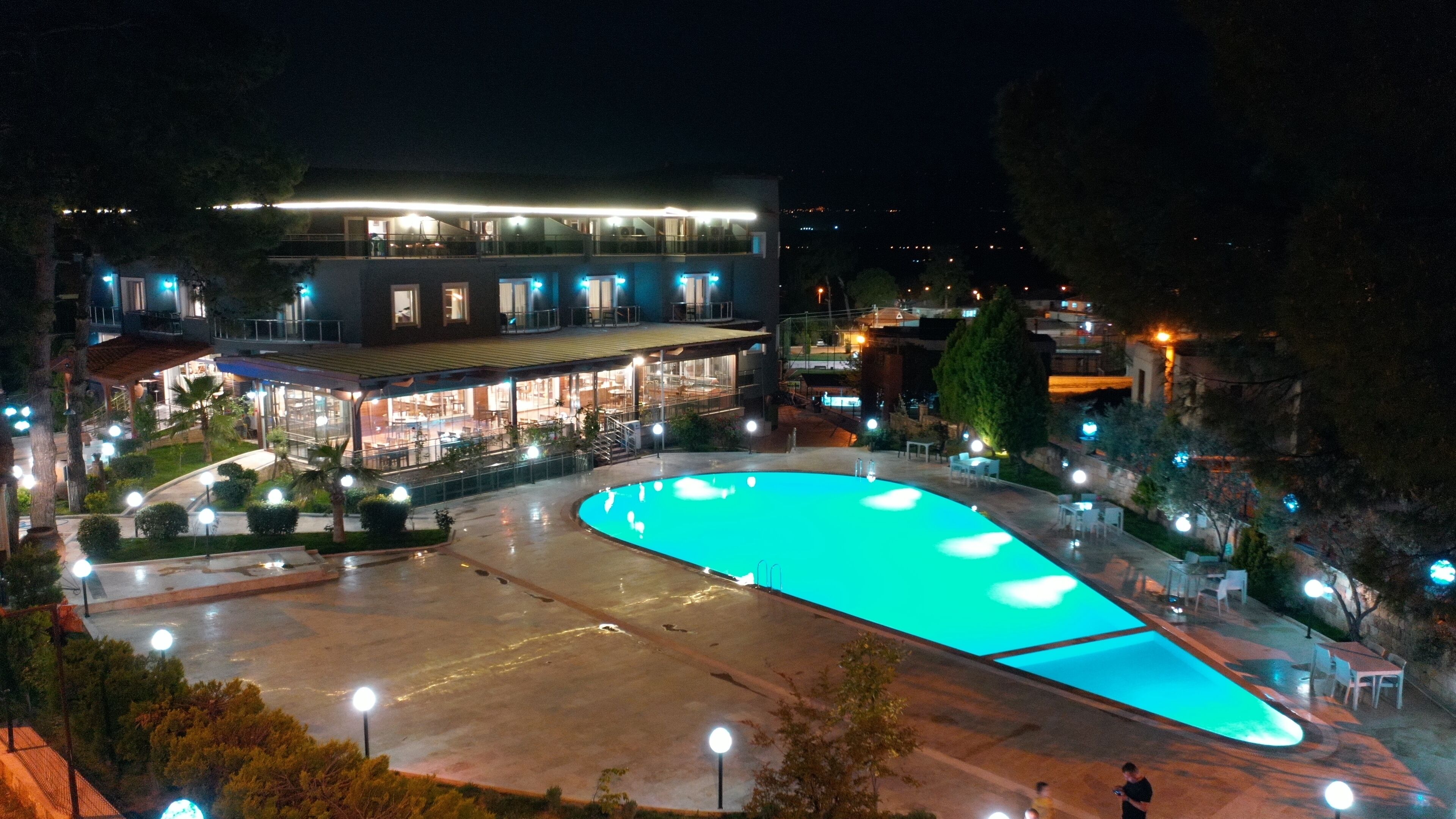 A hotel with a swimming pool, outdoor seating, and a well-lit building.