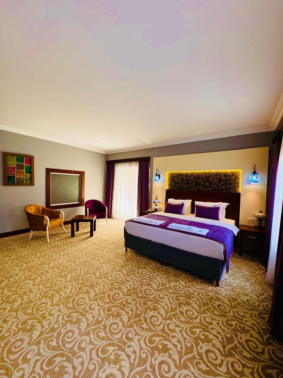 Una habitación de hotel con una cama grande, un escritorio, una silla y un televisor montado en la pared.