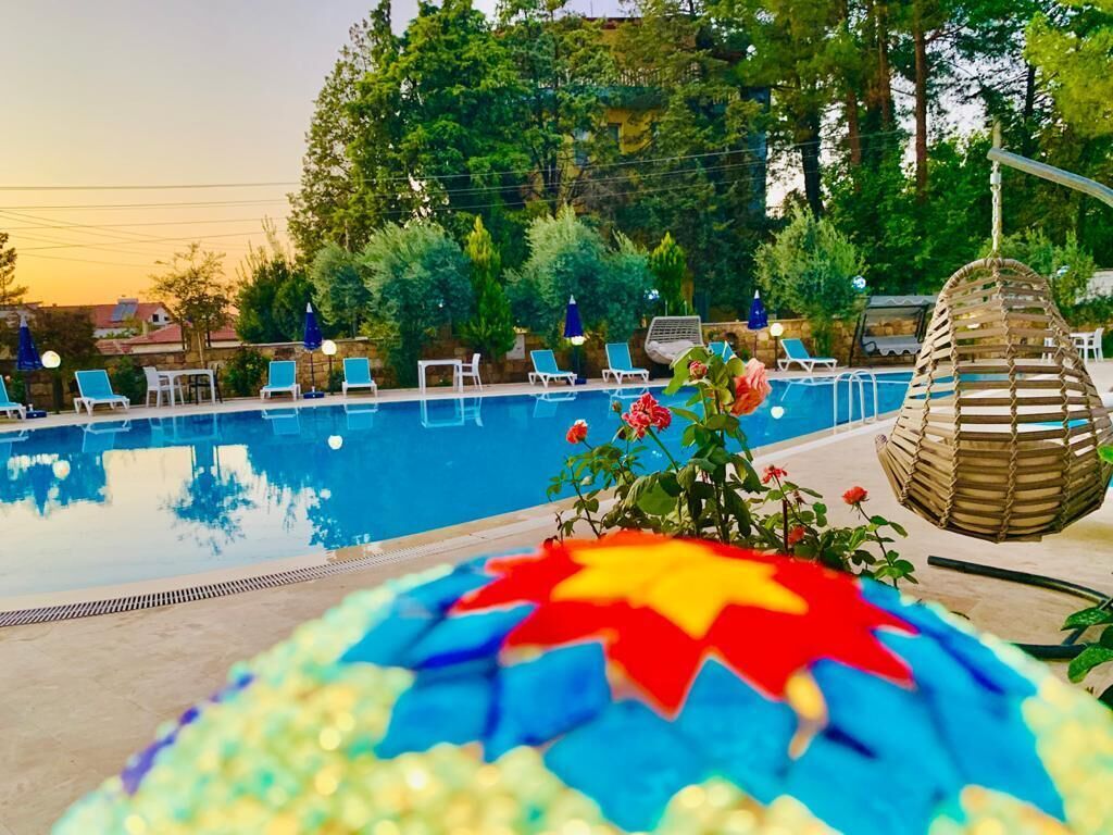 Ein Poolbereich mit Liegestühlen, einem dekorativen Mosaik und einer hängenden Pflanzkorb.