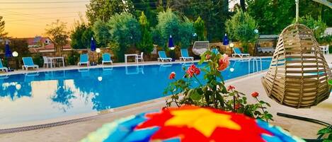 A pool area with lounge chairs, a decorative mosaic, and a hanging basket.