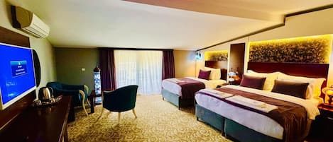 A hotel room with two beds, a desk with a computer, a chair, and a large window with curtains.