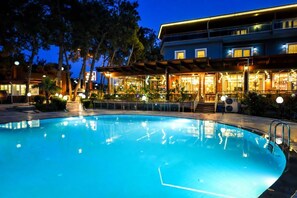 Un hotel moderno con piscina, zona de estar exterior y un patio cubierto.