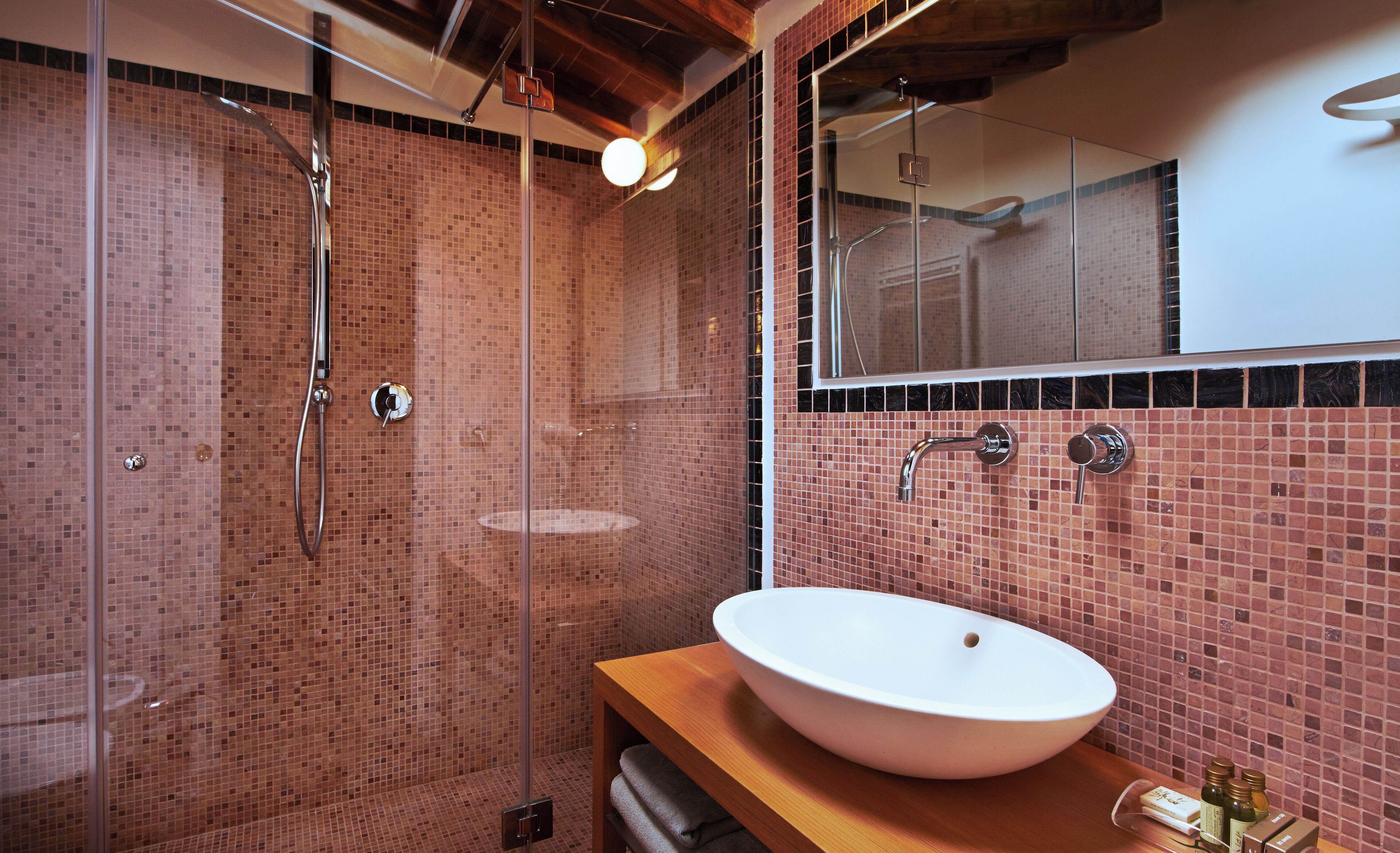A modern bathroom with a glass shower enclosure, a white sink, and a mirror above it.