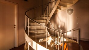 Una escalera de caracol con barandillas de metal en una habitación con suelo de madera y una puerta blanca.