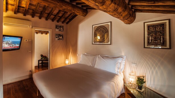 Un dormitorio con techo de madera, una cama, televisor de pared y obras de arte enmarcadas.