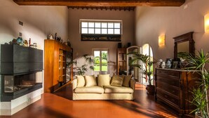 Una sala de estar acogedora con techo de madera, un sofá, una chimenea y un ventanal grande.