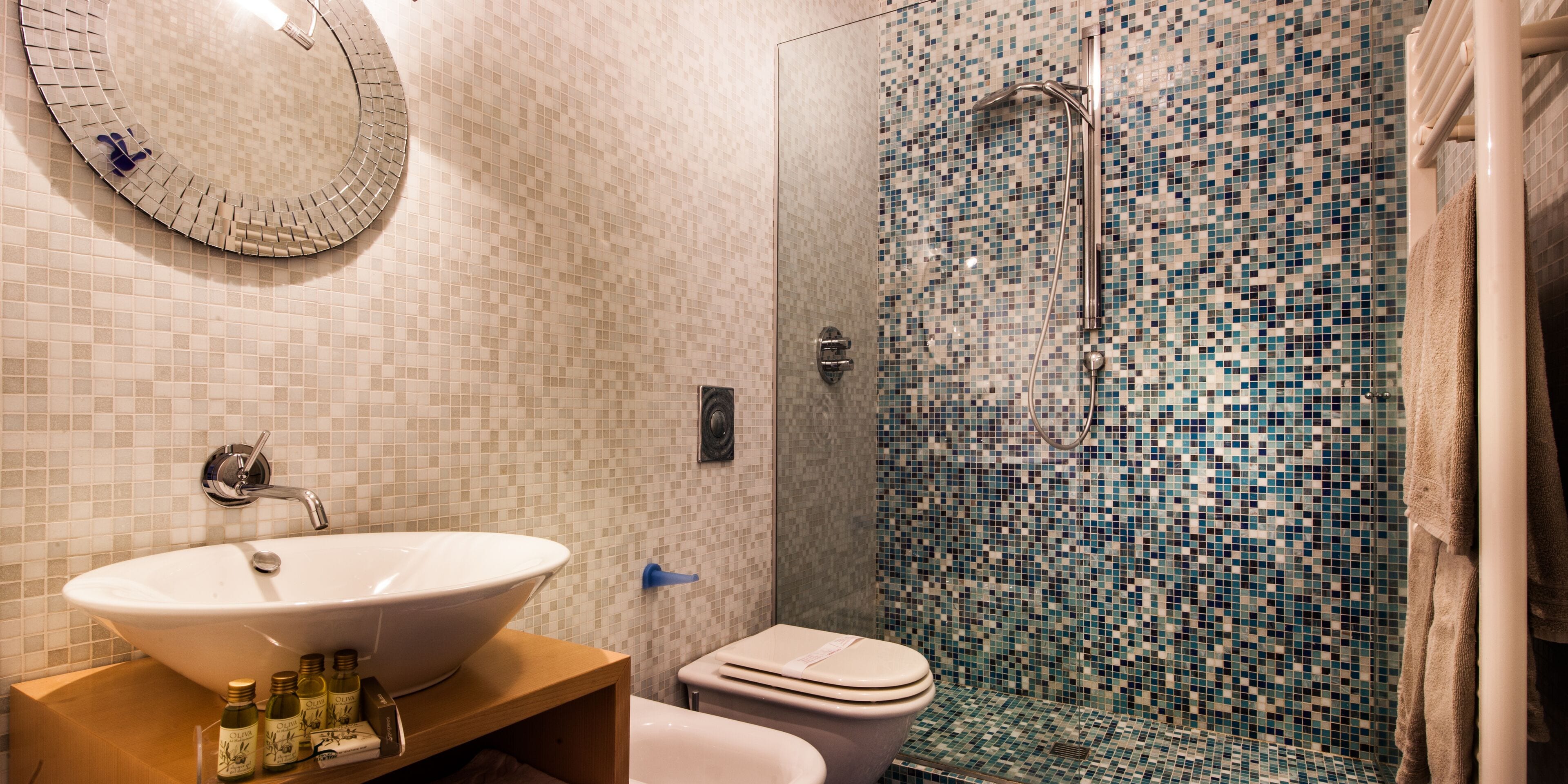 A bathroom with a white sink, a toilet, and a shower with mosaic tiles.