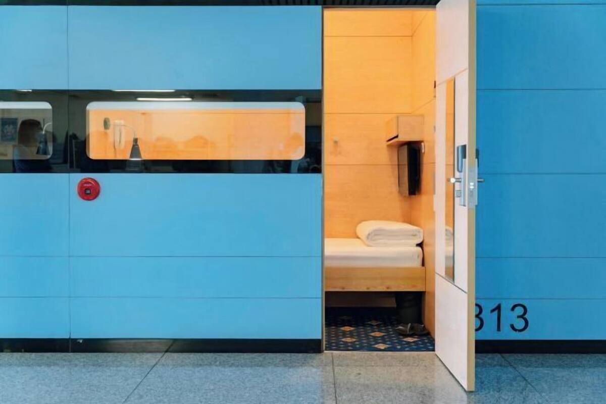 A blue room with a bed, a small table, and a wall-mounted shelf.