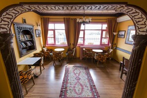Un área de comedor con una mesa y sillas de madera, una estantería y un tapete estampado.