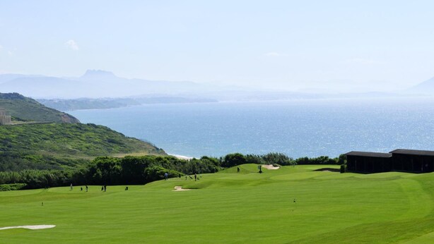 A golf course with a view of the ocean and distant mountains.