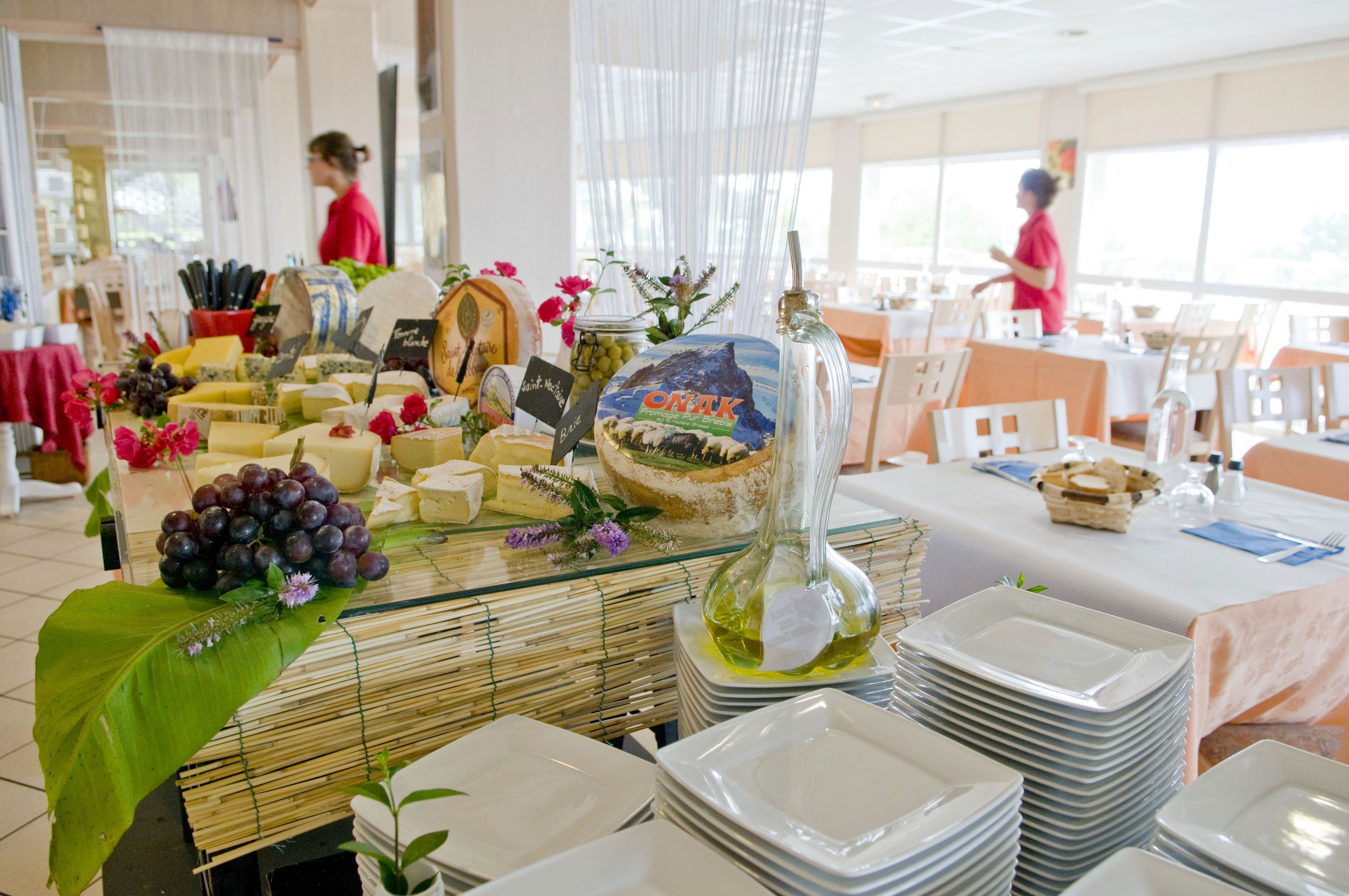Una mesa de buffet con varios quesos, frutas y una botella decorativa.