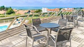 A deck with outdoor seating and a view of the ocean.