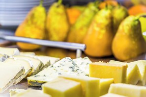 A variety of cheeses and pears on a wooden board.