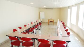 A conference room with long tables, red chairs, and a whiteboard.