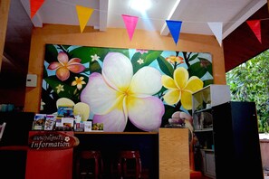 A reception area with a large floral mural, a wooden counter, and a sign labeled "Information".