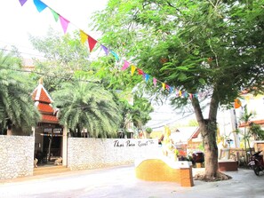 A Thai resort entrance with a stone wall, a gate, and a sign.