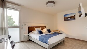 Ein modernes Hotelzimmer mit einem Bett, einem Nachttisch und einem Schreibtisch mit Stuhl.