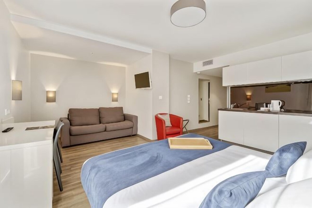 Une chambre d’hôtel moderne équipée d’un lit, d’un bureau, d’un canapé et d’une kitchenette.