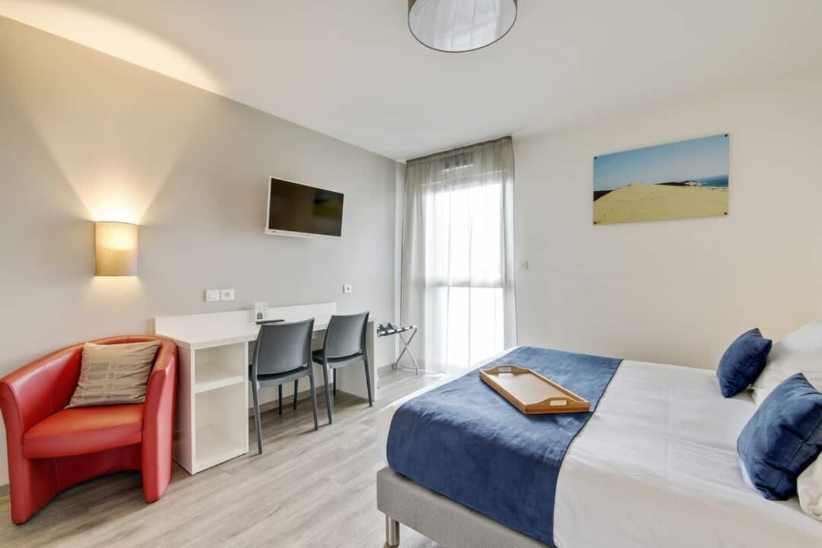 Ein Hotelzimmer mit Bett, Schreibtisch, Stuhl und Fernseher.