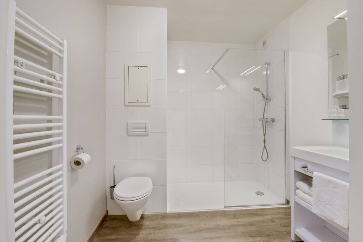 Ein modernes Badezimmer mit Toilette, Dusche und einer Duschkabine.