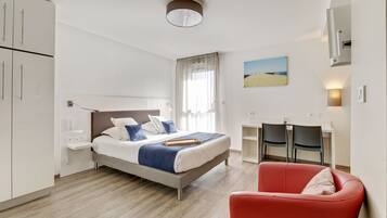 Een hotelkamer met een bed, een bureau, een stoel en een rode fauteuil.