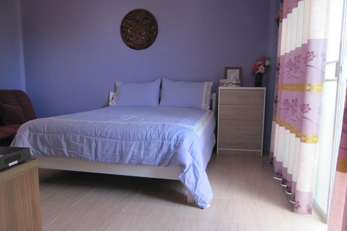 A bedroom with a bed, a dresser, a chair, and a wall decoration.