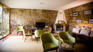 Una sala de estar con paredes de piedra, chimenea y televisión.