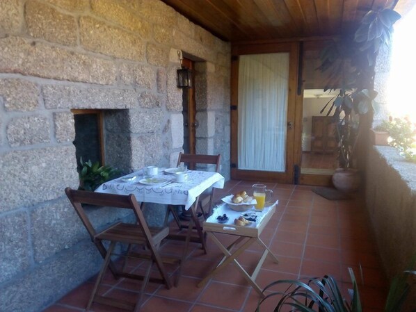 A stone-walled patio with a table set for breakfast, including plates, cups, and a pitcher of orange juice. - Quinta de Lourosa (Lousada)