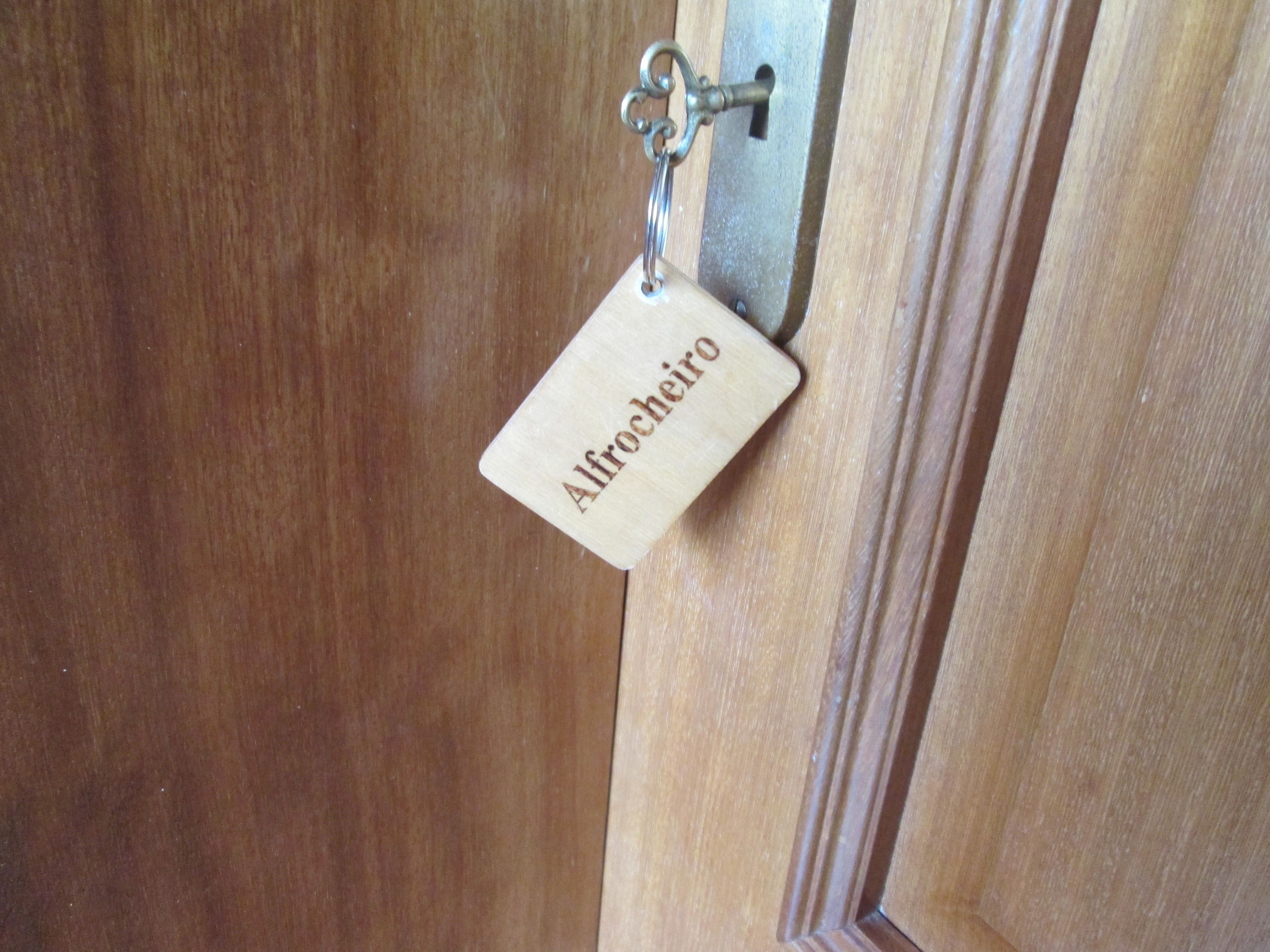 A wooden door with a keyhole and a metal plate with the name "Alfredo" engraved on it.