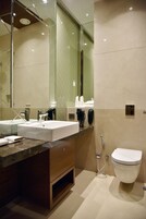 Een moderne badkamer met een grote spiegel, twee wastafels, een toilet en een douche.