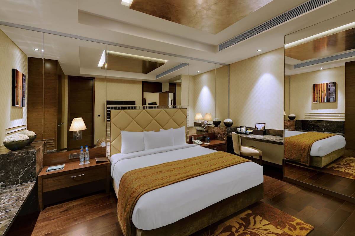 Ein Hotelzimmer mit einem großen Bett, einem Schreibtisch, einem Stuhl, einem Spiegel und einem Badezimmer.