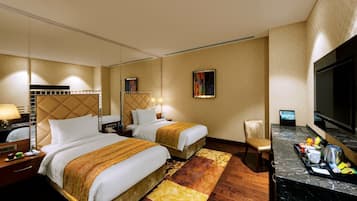 A hotel room with two beds, a TV, a desk with a coffee maker, and a tray with breakfast items.