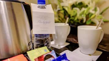 Una estación de café con una máquina Nespresso, una botella de agua y una taza con pajita.