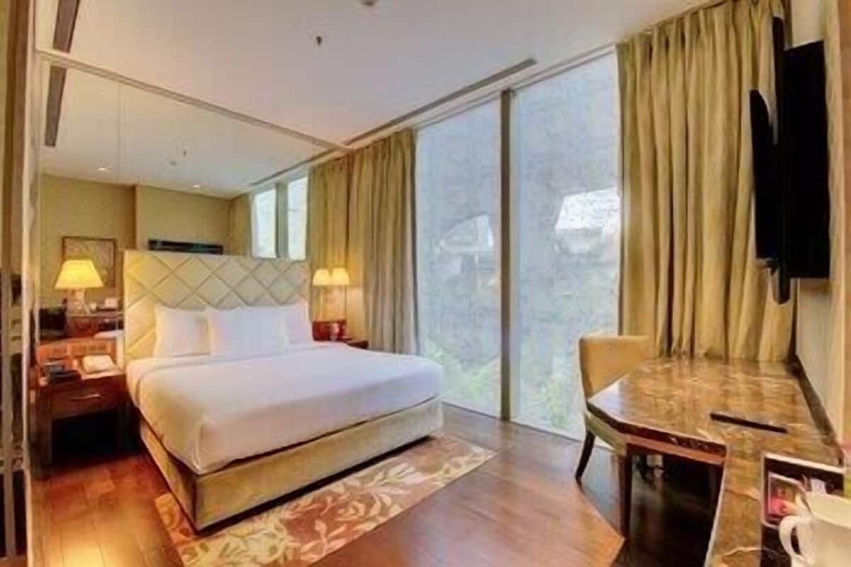 Ein Hotelzimmer mit Bett, Nachttischen, Schreibtisch, Stuhl und Fernseher.