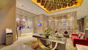 A modern hotel lobby with a reception desk, seating area, and decorative elements.