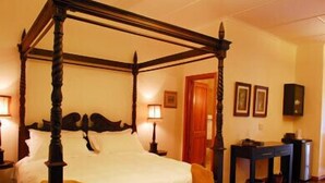 Una cama con dosel de madera y ropa de cama blanca en una habitación de hotel.